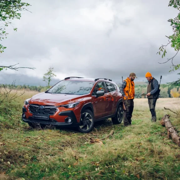 Subaru Crosstrek i terräng, jägare planerar jakt vid bilen i skogsmiljö.