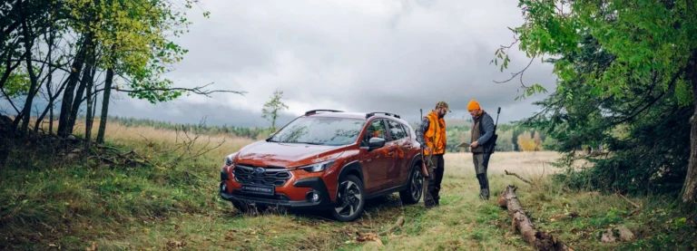 Subaru Crosstrek i terräng, jägare planerar jakt vid bilen i skogsmiljö.