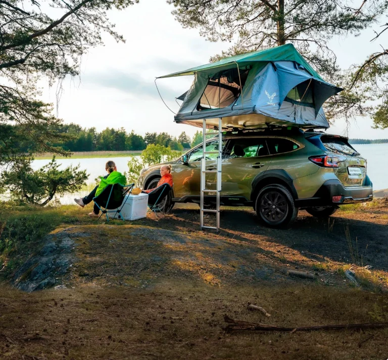 Camping vid sjö med Subaru Outback och uppfällt taktält.